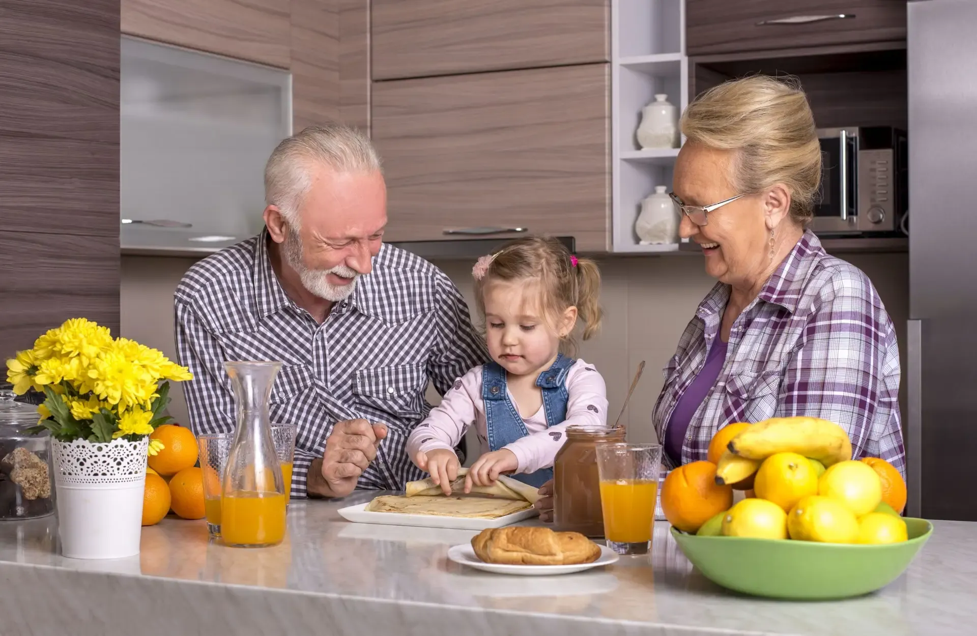 A granddaughter and her grandparents cooking together in the kitchen